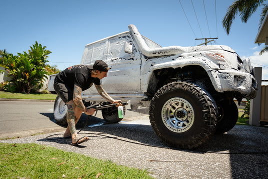 4WD ute covered in thick foam wash, breaking down dirt and grime for a deep clean.