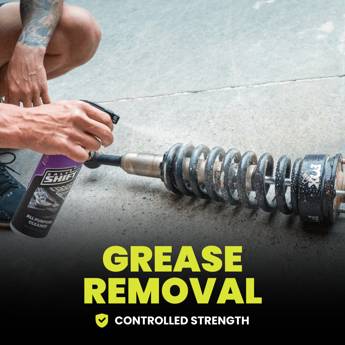Person using a spray bottle to remove grease from a metal barbell on a concrete floor.