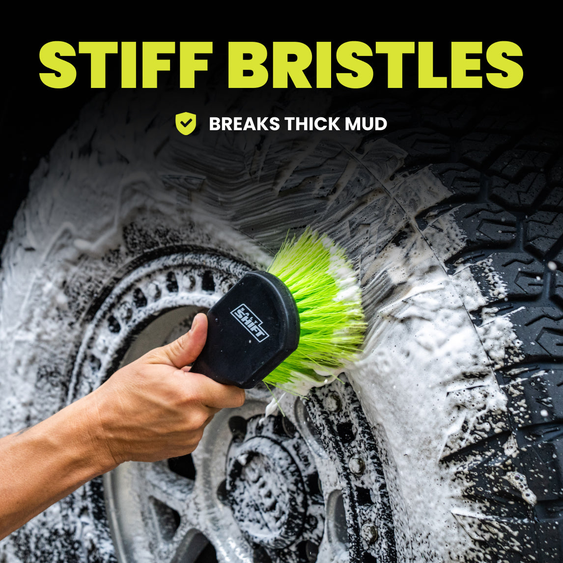 Person cleaning a muddy tire with a brush labeled 'Stiff Bristles' on a black background.