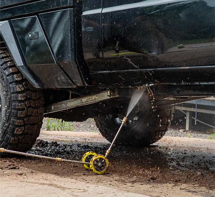 Black truck being cleaned with a pressure washer on a dirt surface
