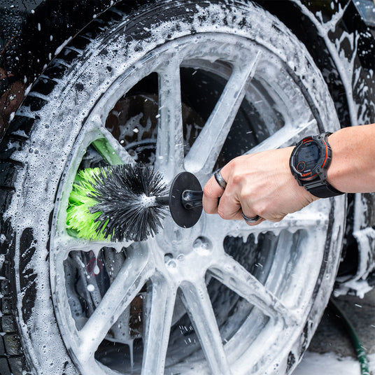 Person cleaning a car wheel with a brush