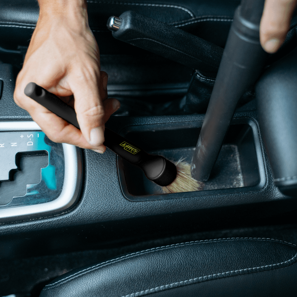 A person uses a Salt Shift detailing brush to clean a car.