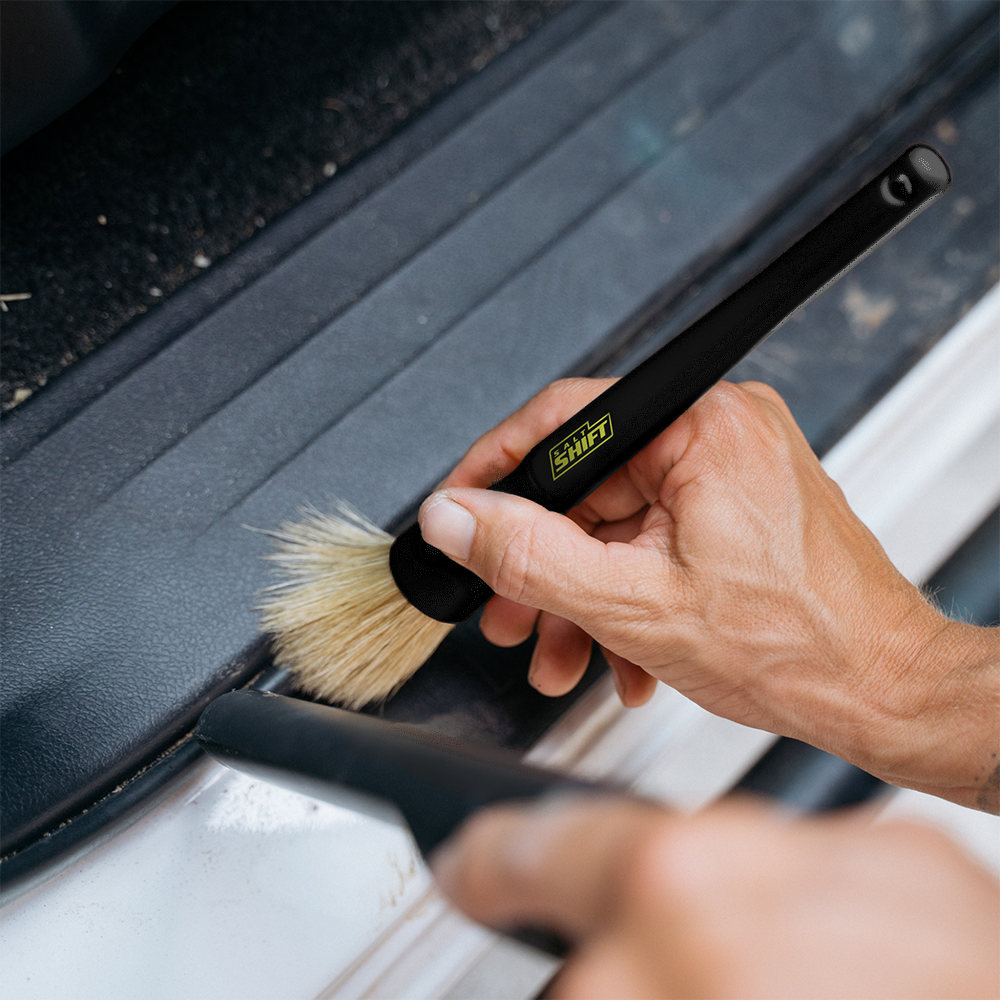 A person uses a Salt Shift detailing brush to clean a car.