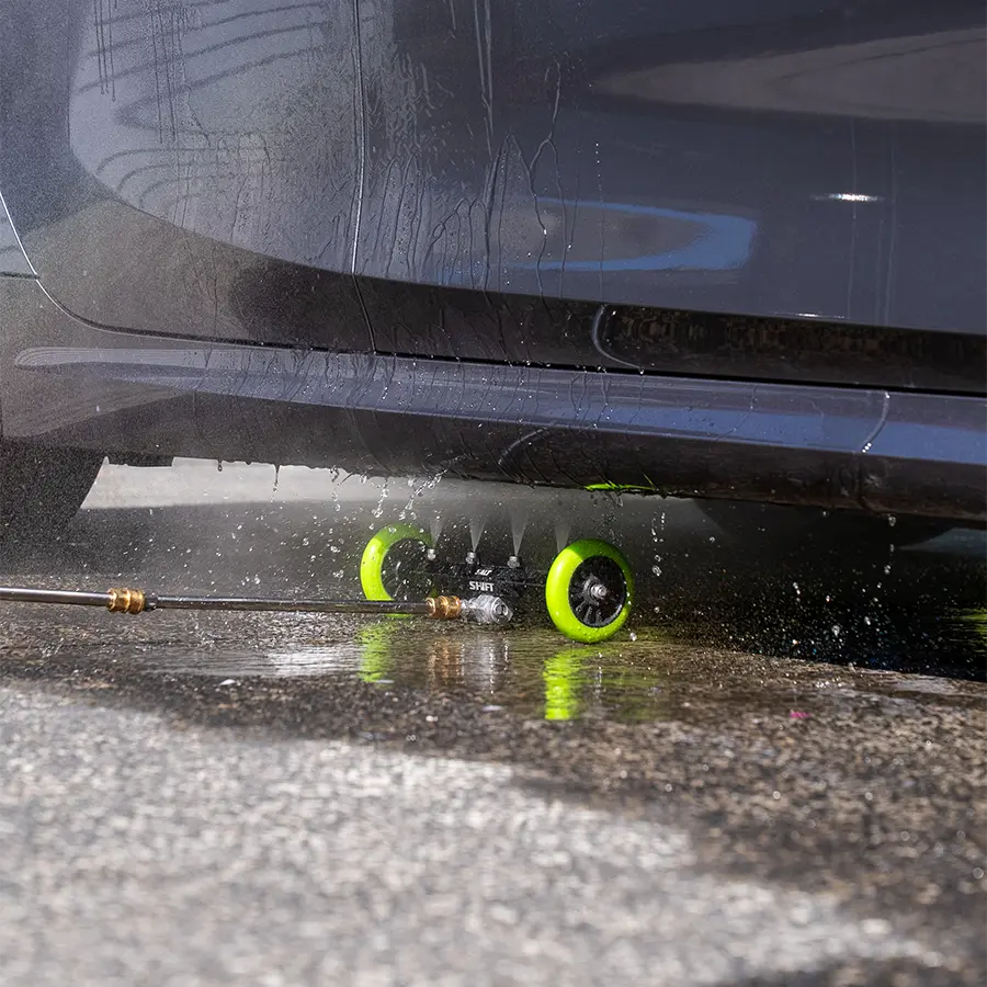 Car wash brush with green wheels on a car's undercarriage