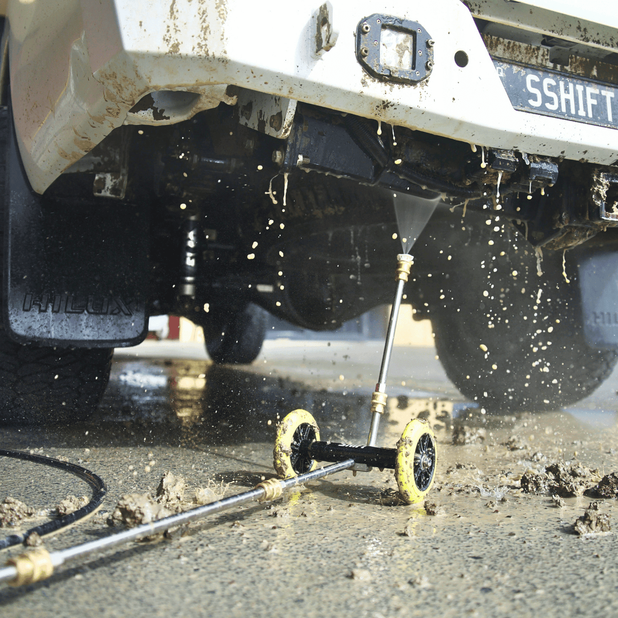 High-pressure underbody wash cleaning a 4x4 vehicle, removing dirt and grime for off-road maintenance and protection.