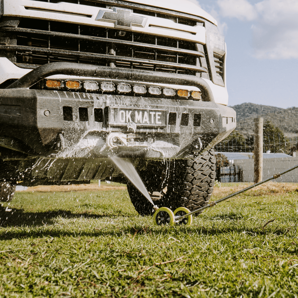High-pressure underbody wash cleaning a 4x4 vehicle, removing dirt and grime for off-road maintenance and protection.