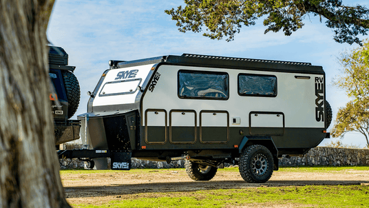 Skye off-road camper trailer parked on a grassy area with trees in the background