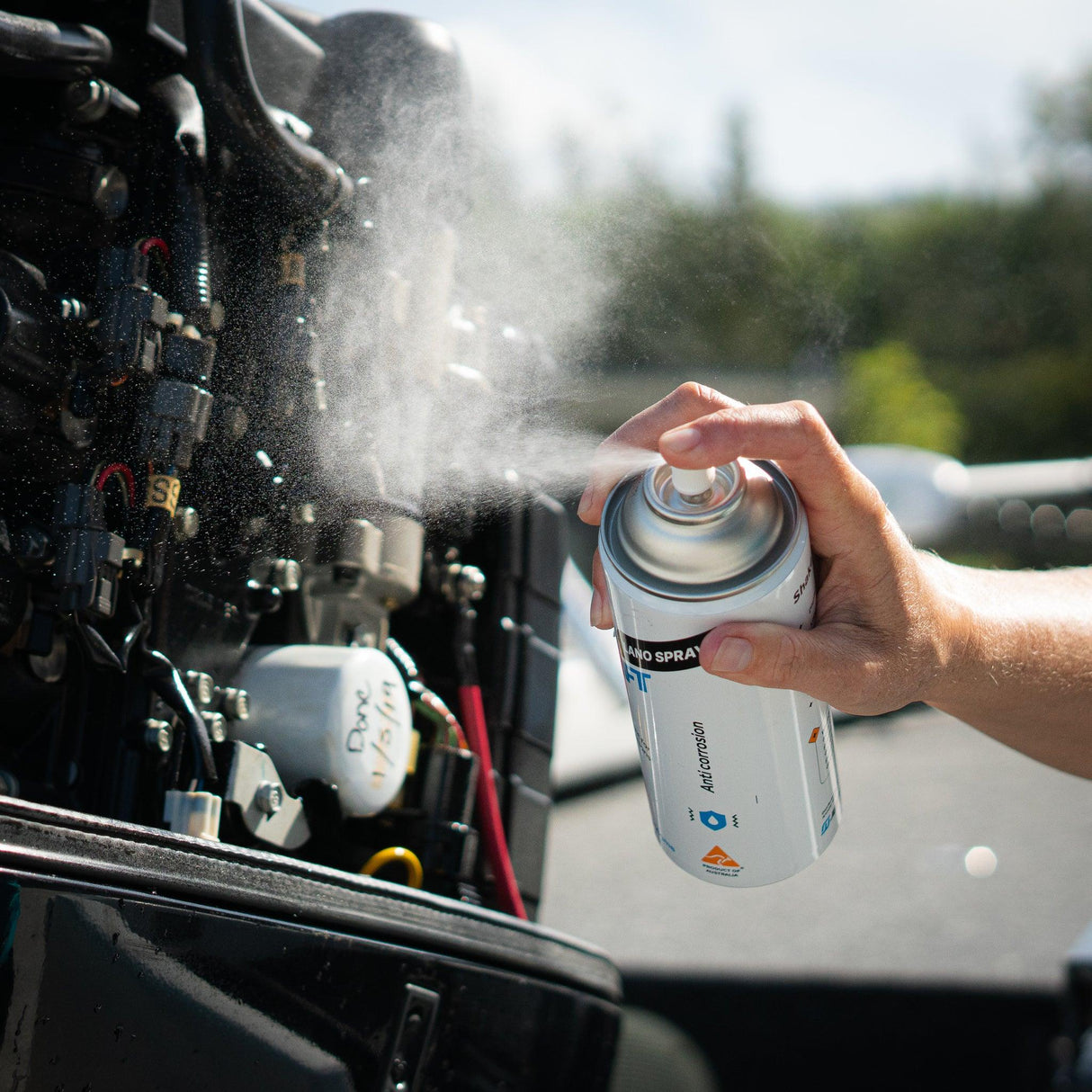 A person sprays Salt Shift Nano Spray on a boat engine for anti-corrosion protection.