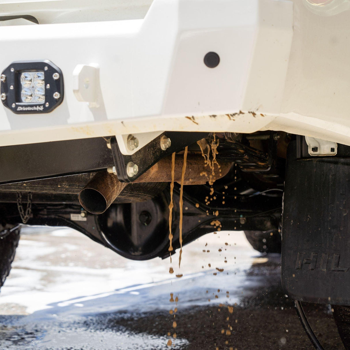Dirty water drains from a 4x4 chassis after using a Salt Shift underbody wash.