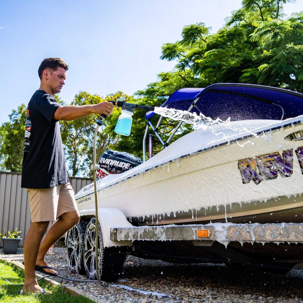 Man using a foam gun to wash a boat with Salt Shift cleaning solution, removing salt and grime for corrosion protection.