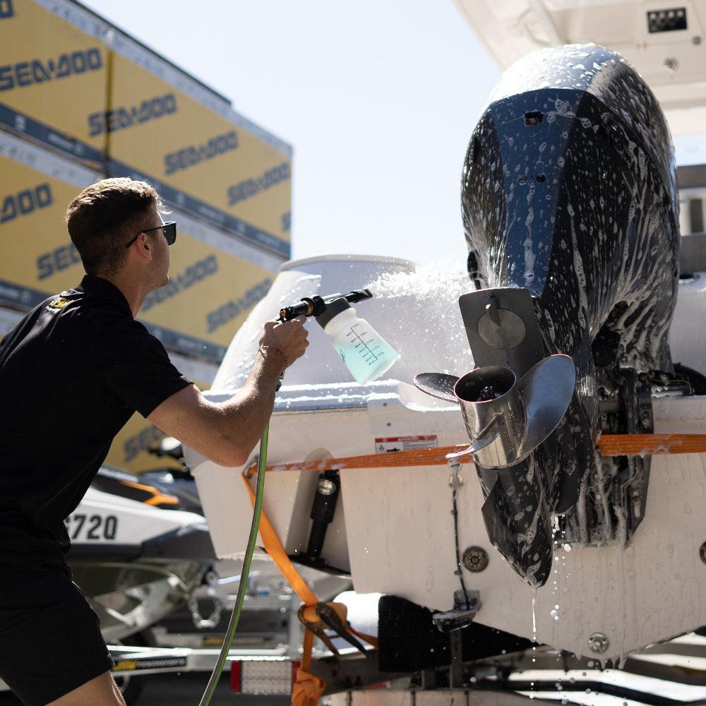 A person uses a Salt Shift foam cannon to spray a boat with cleaning foam.