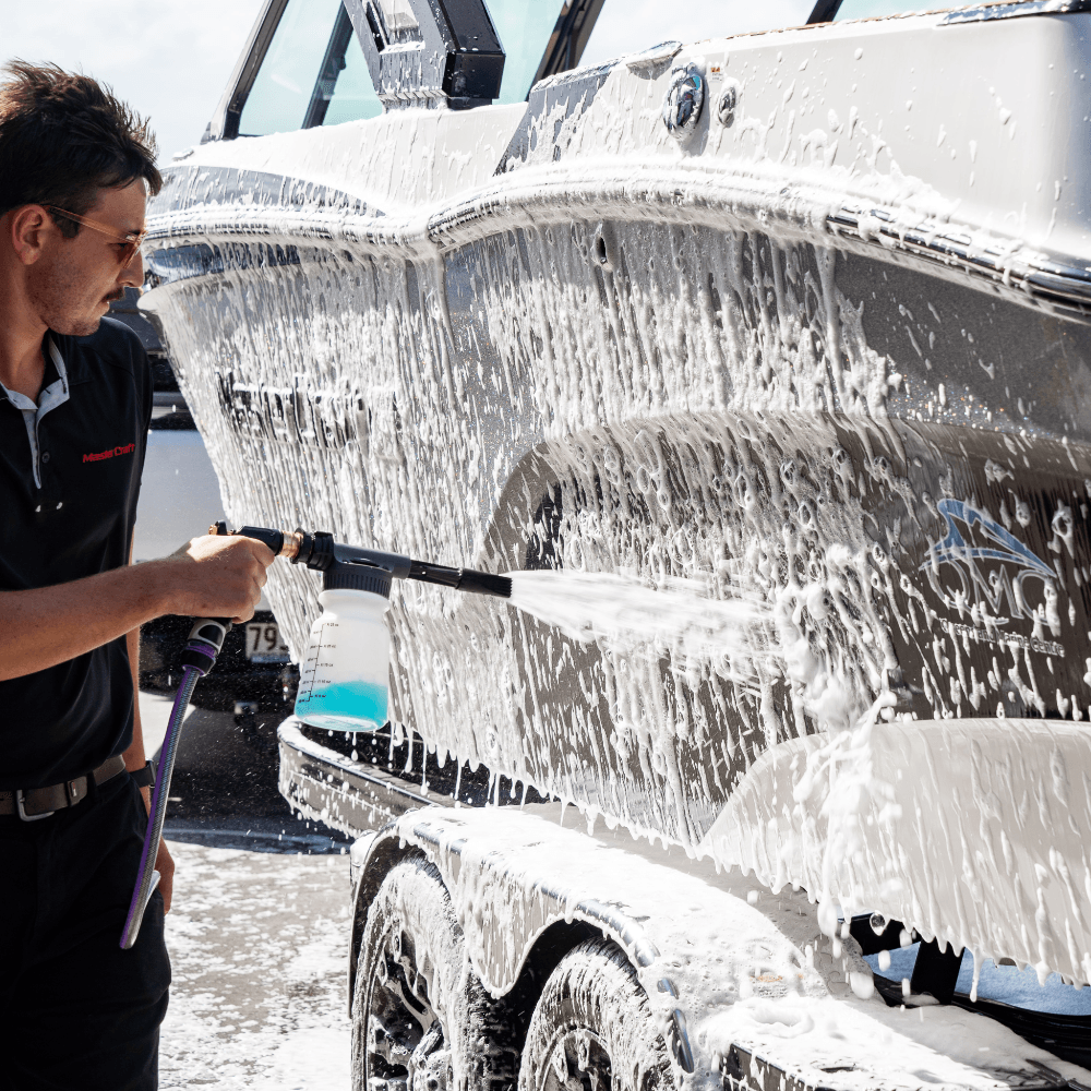 Man using a foam gun to wash a boat with Salt Shift cleaning solution, removing salt and grime for corrosion protection.