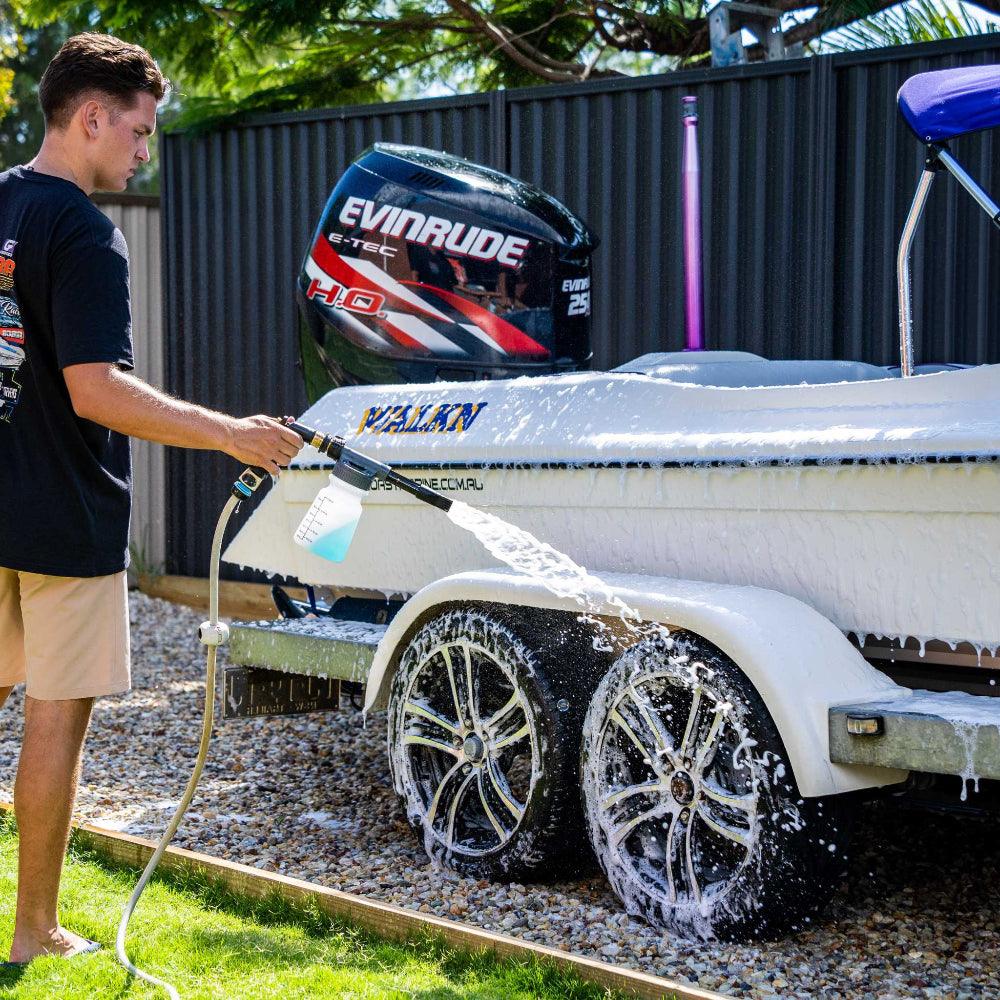 Man using a foam gun to wash a boat with Salt Shift cleaning solution, removing salt and grime for corrosion protection.
