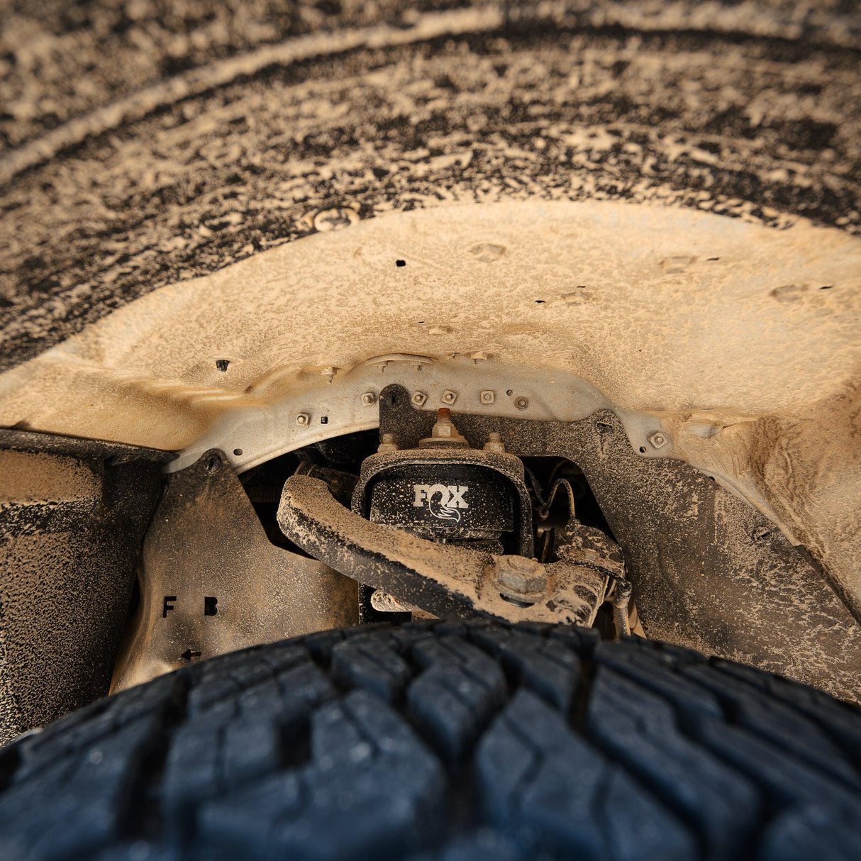 A 4x4 wheel well covered in sand and ready to by cleaned with Salt Shift cleaning foam.