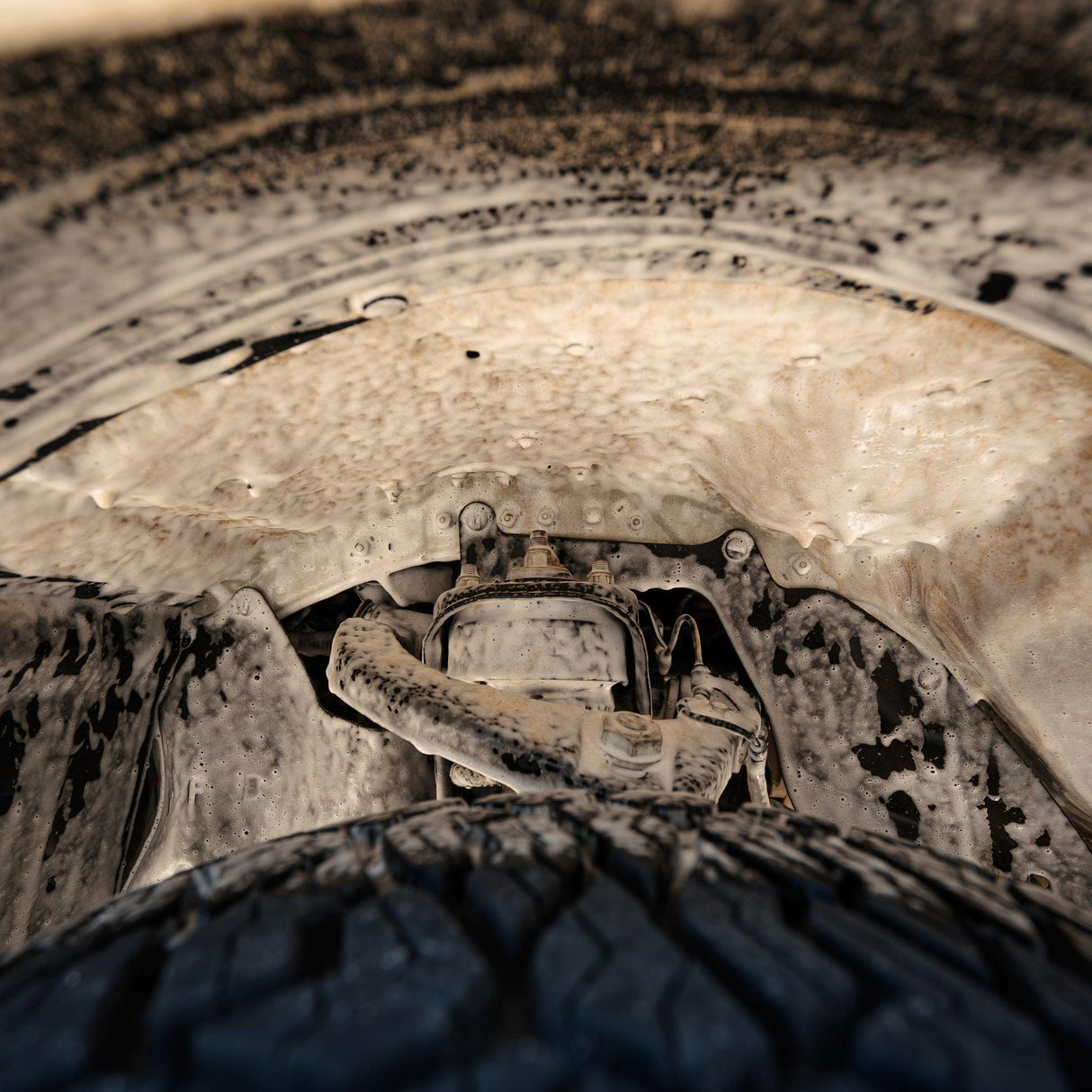 A 4x4 wheel well covered in Salt Shift cleaning foam, breaking down dirt and grime.