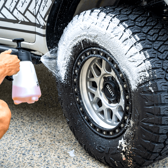 A 4x4 wheel well being washed in Salt Shift cleaning foam, breaking down dirt and grime.