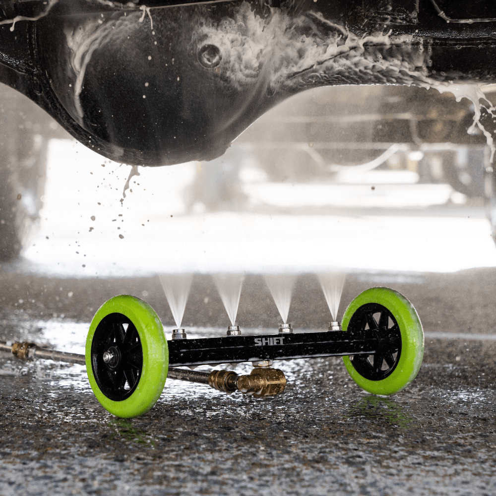 A person uses a Salt Shift underbody washer to clean a chassis.