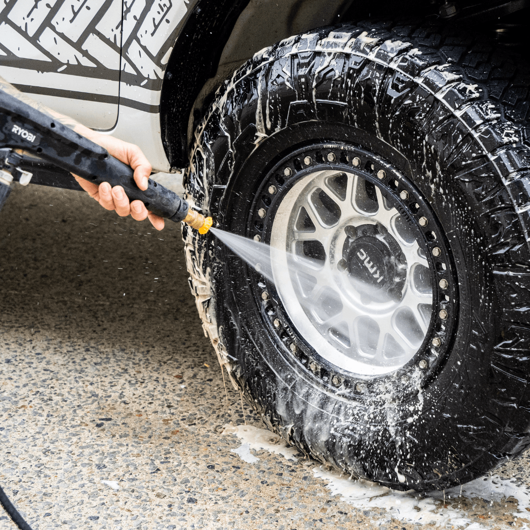 A 4x4 wheel well being washed in Salt Shift cleaning foam, breaking down dirt and grime.