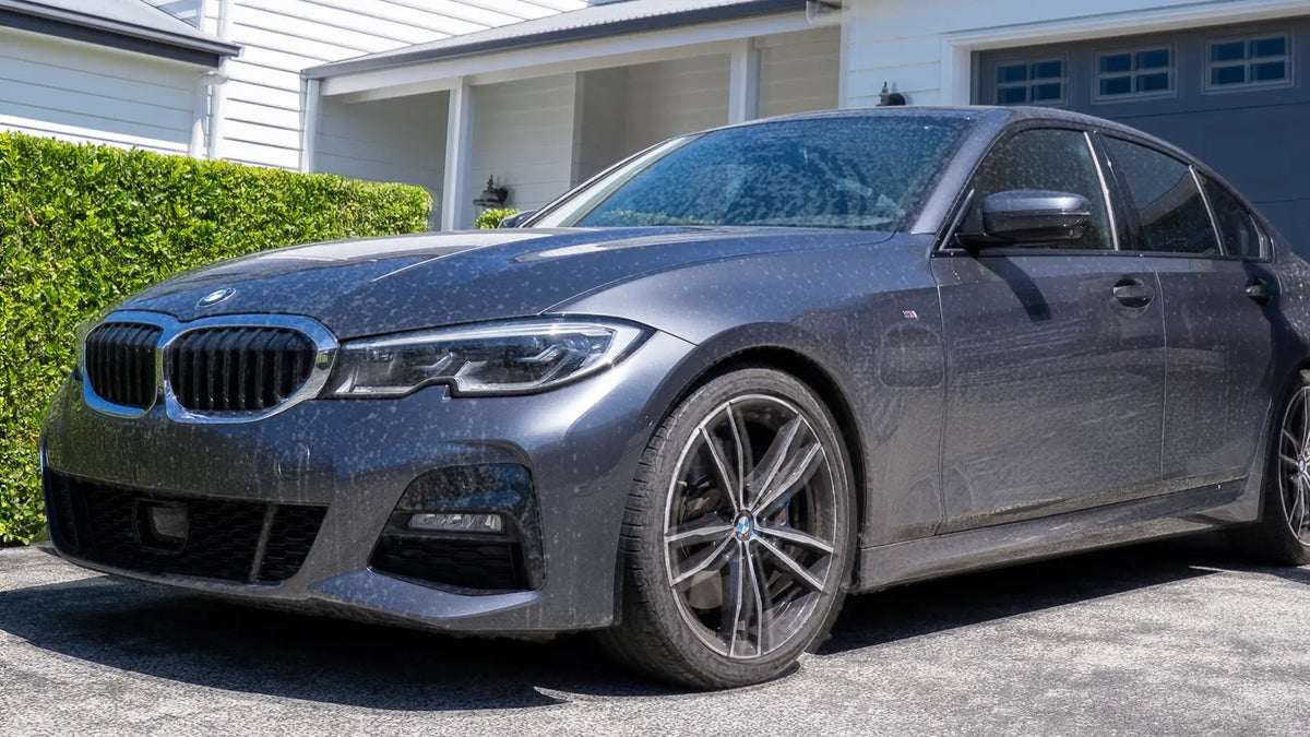 Car with water droplets on a driveway in front of a house