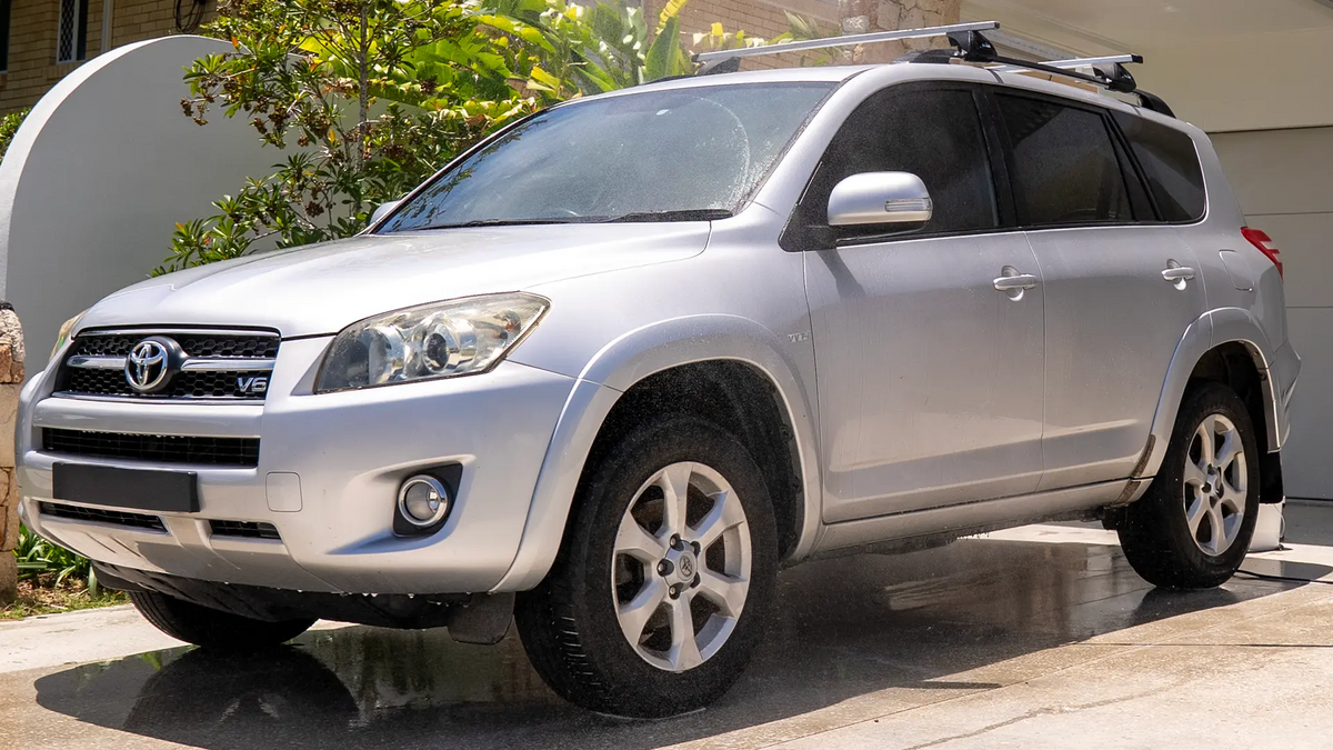 Silver Toyota SUV parked on a driveway with a house and plants in the background