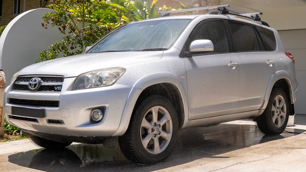 Silver Toyota SUV parked on a driveway with a house and plants in the background