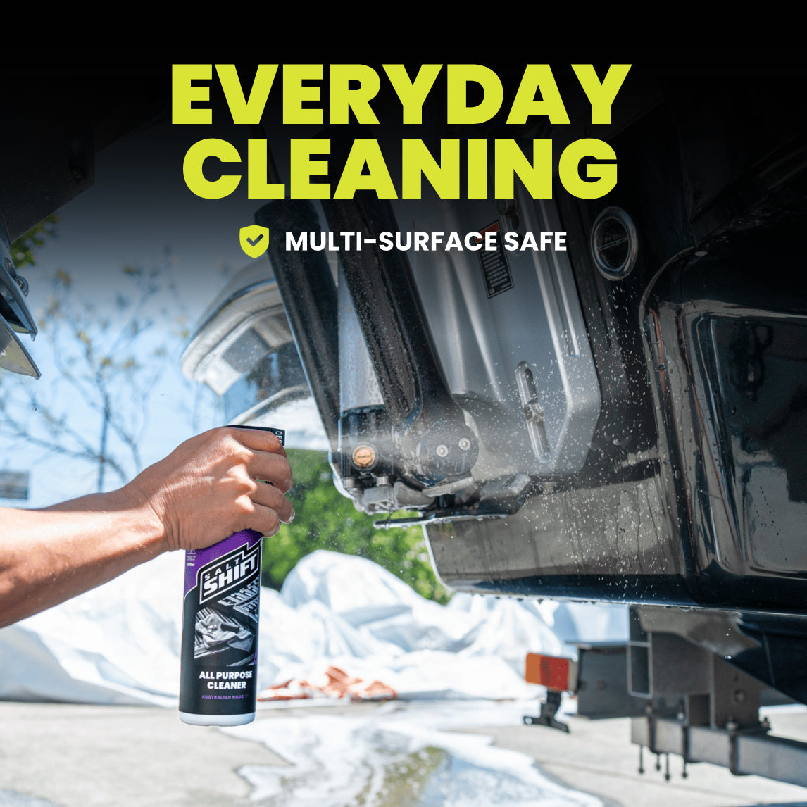 Person cleaning an RV with a spray bottle labeled 'All Purpose Cleaner' on a sunny day.