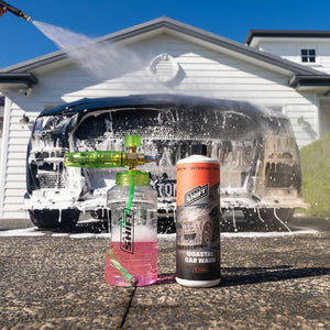 Car washing setup with a pressure washer and cleaning products in front of a house.