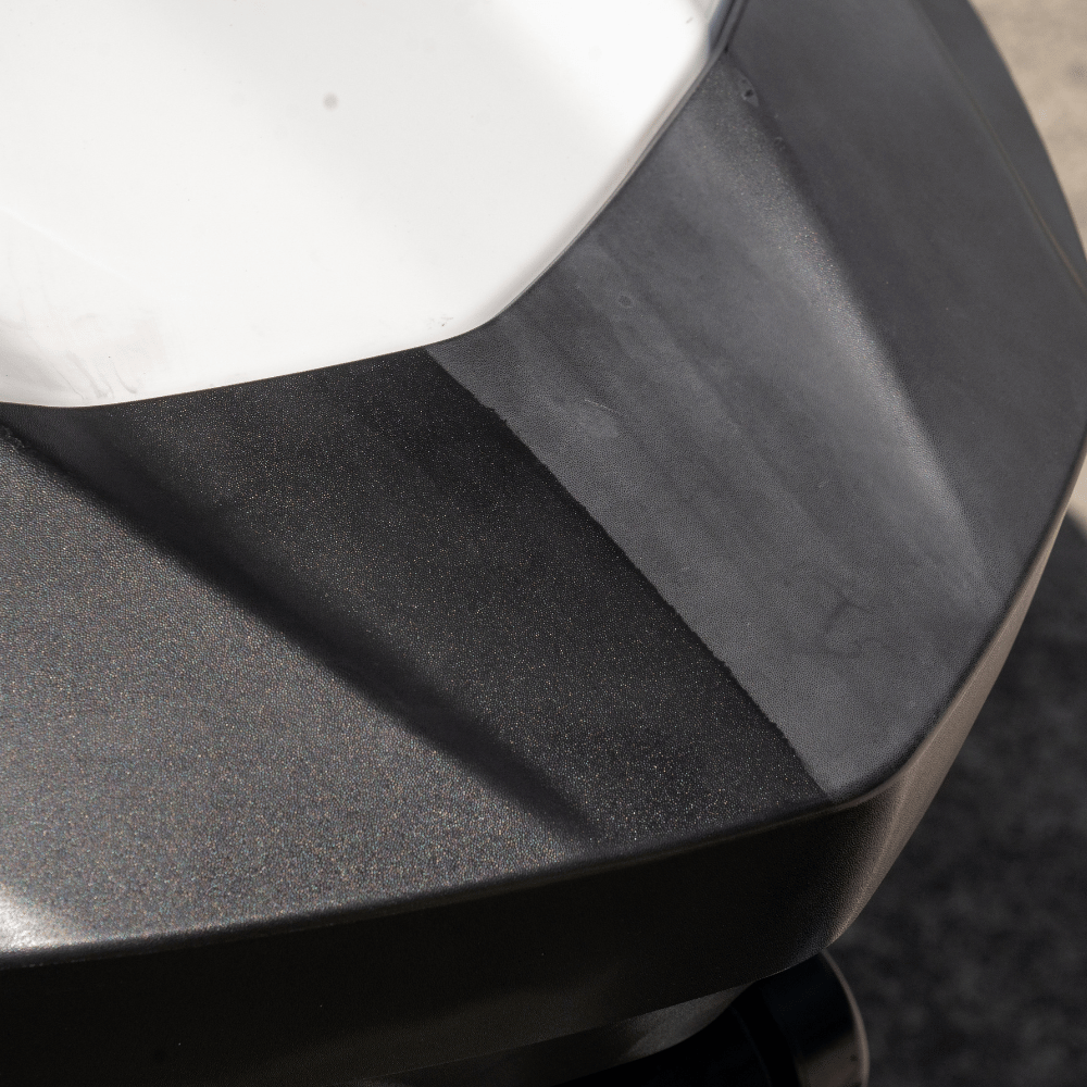 Close-up of a black car bumper with a white edge.