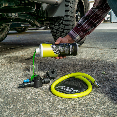 Person using a can of Goop to apply it to a vehicle's exhaust system.