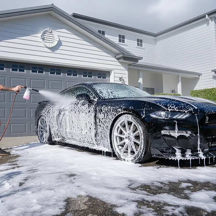 Car being washed with a soapy solution in front of a house