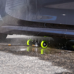 Car wash brush with green wheels on a car's undercarriage
