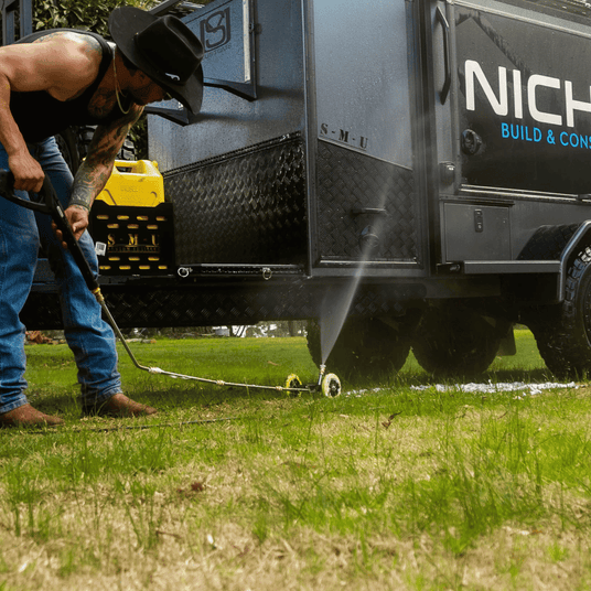 High-pressure underbody wash cleaning a caravan vehicle, removing dirt and grime for off-road maintenance and protection.