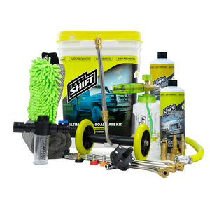 A comprehensive car care kit displayed on a clean white background, featuring a large white bucket with a bright yellow lid and label, a green microfiber wash mitt, brass nozzles and hoses, a pressure washer wand, a foam cannon, bottles of cleaning solutions, and a gray sponge.