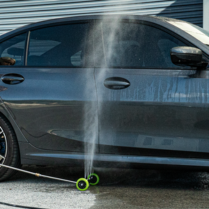 Car being washed with a high-pressure water gun on a sunny day.