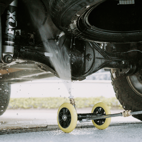 High-pressure underbody wash cleaning a 4x4 vehicle, removing dirt and grime for off-road maintenance and protection.