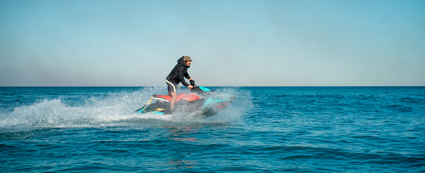 Person riding a jet ski on a clear blue ocean with a clear sky.