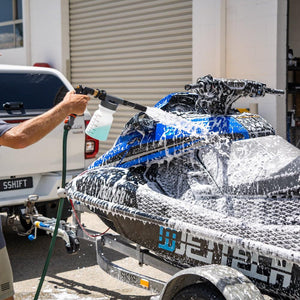 Man using a foam gun to wash a jetski with Salt Shift cleaning solution, removing salt and grime for corrosion protection.