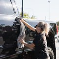 A person wipes down a truck with a grey microfibre towel, ensuring a clean and polished finish.