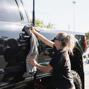 A person wipes down a truck with a grey microfibre towel, ensuring a clean and polished finish.
