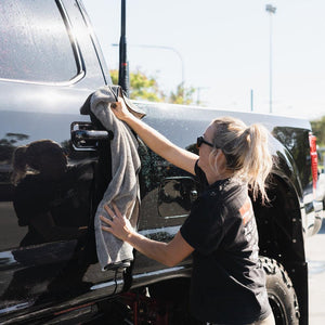 A person wipes down a truck with a grey microfibre towel, ensuring a clean and polished finish.
